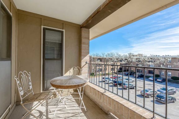 a balcony with a table and chairs overlooking a parking lot