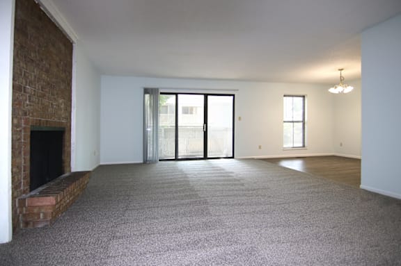 A large, empty room with a fireplace on the left side.