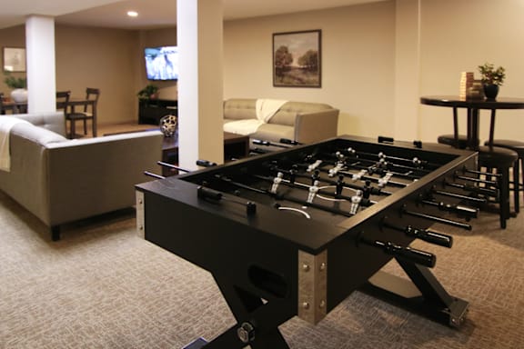 A foosball table in a living room with a couch and a television in the background.