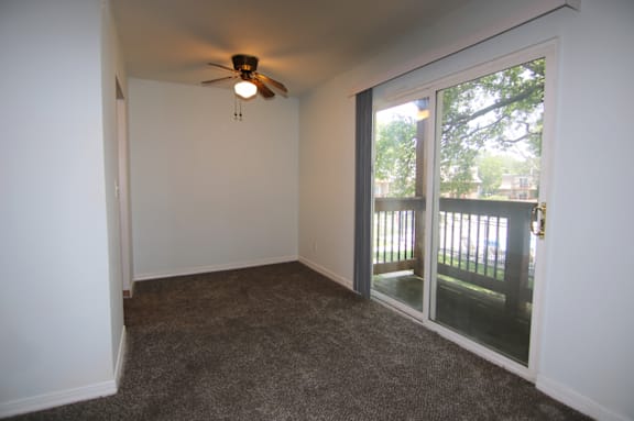 A room with a ceiling fan and sliding glass doors.
