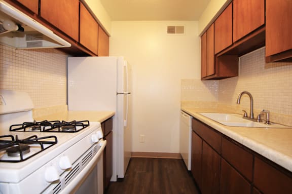 A kitchen with a white gas stove and a white refrigerator.
