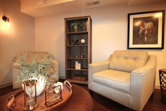 A living room with a sofa, a chair, a coffee table, and a bookshelf.