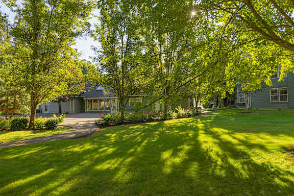 A house with a green lawn and trees in front of it.