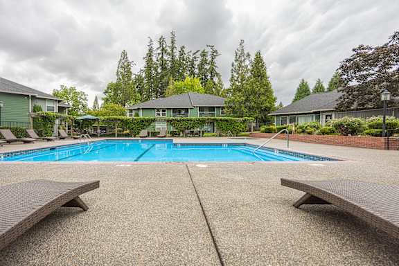 A pool surrounded by benches and trees.