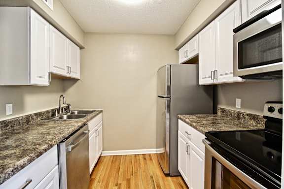 A kitchen with a granite counter top and stainless steel appliances.