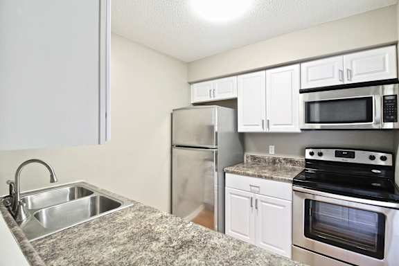 A kitchen with a stove, sink, and refrigerator.
