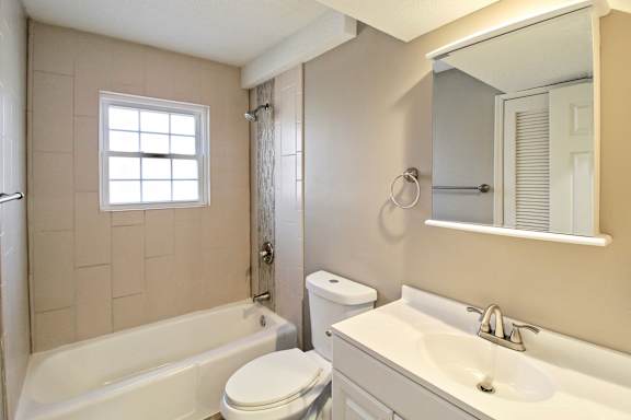 A white toilet sits next to a bathtub in a bathroom.