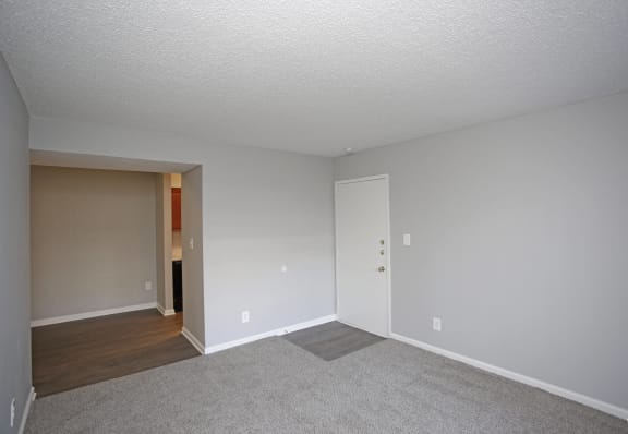 an empty living room with a door into a hallway