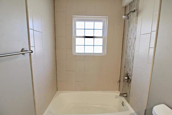 A white bathroom with a tub, toilet, and shower.
