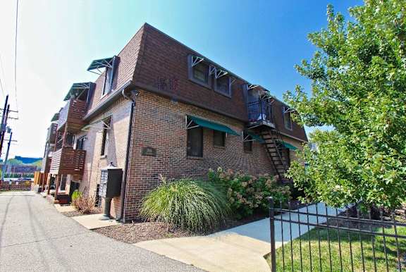 A brick building with a green awning and a black fence.
