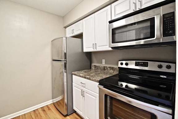 A kitchen with a stove, microwave, and refrigerator.