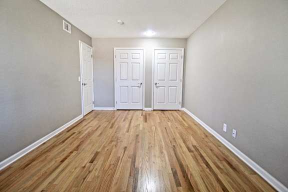 A room with wooden floors and two white doors.
