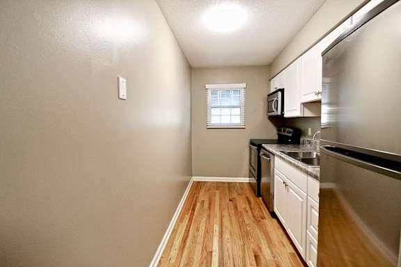 A kitchen with wooden floors and white cabinets.