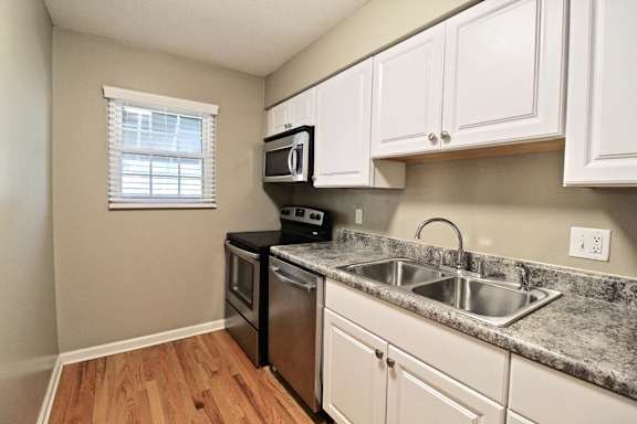 A kitchen with a sink, stove, and microwave.