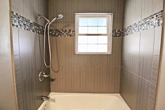 A bathroom with a shower, tub, and a window.