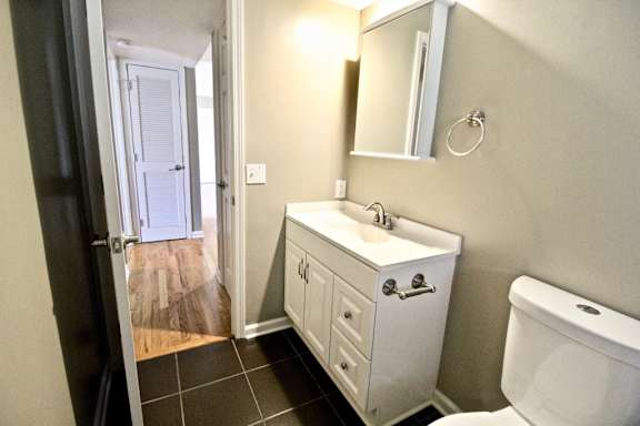 A white bathroom with a sink, mirror, and toilet.