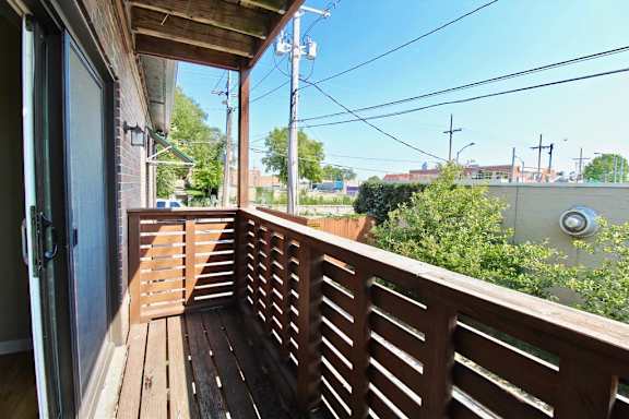 A wooden deck with a door and a view of the street.