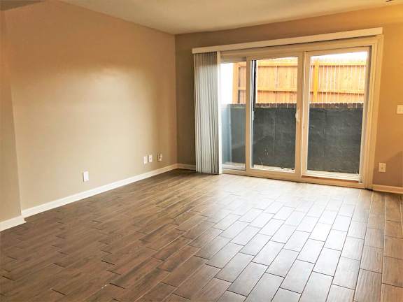 A room with a sliding glass door and wooden flooring.