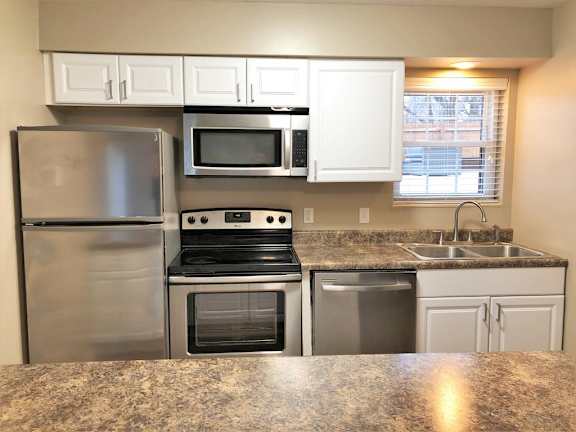 A kitchen with a granite countertop and stainless steel appliances.