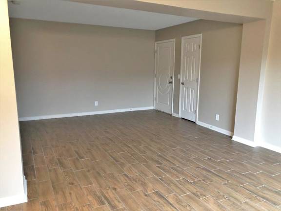 A room with wooden flooring and two white doors.