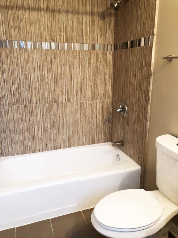 A white toilet sits next to a bathtub in a bathroom.