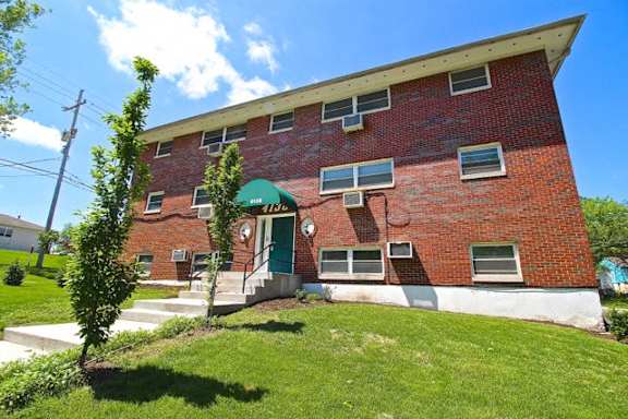 A red brick building with a green awning and a white door.