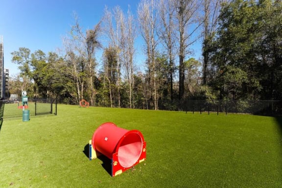 a red trash can sitting on top of a lush green field  at Fusion, Florida, 32256
