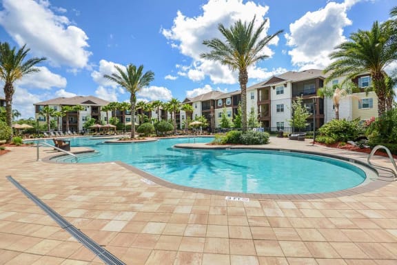 a swimming pool with palm trees in front of an apartment complex  at Cabana Club - Galleria Club, Jacksonville, FL, 32256