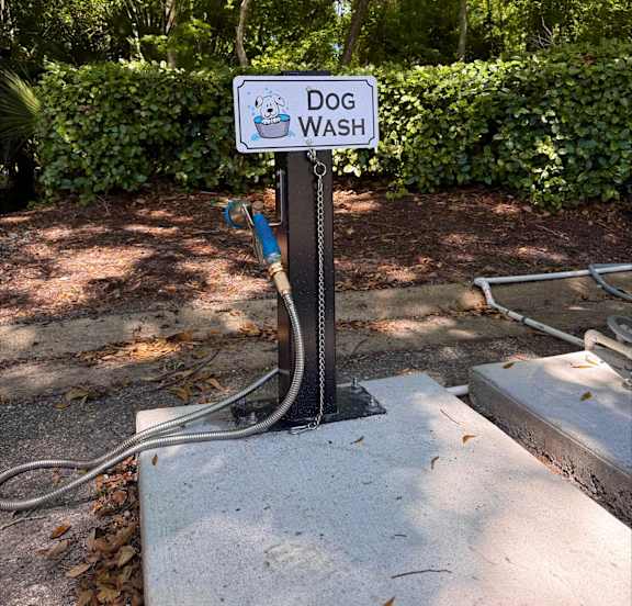 A dog wash station with a sign and hose.