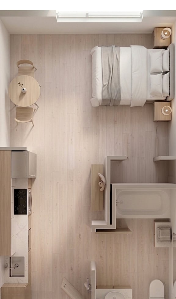 A studio apartment with a bed, table, kitchen sink, and bathroom