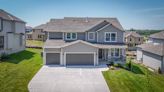 A large house with a garage is surrounded by other houses.