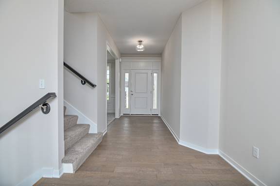 A long hallway with a staircase on the left and a door at the end.