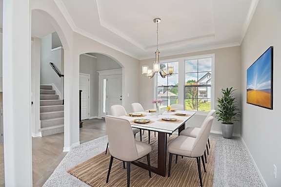 A dining room with a table set for six with a view of the backyard.