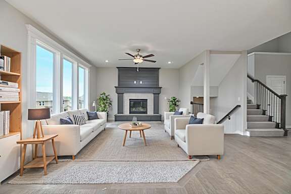 A living room with a fireplace and a ceiling fan.