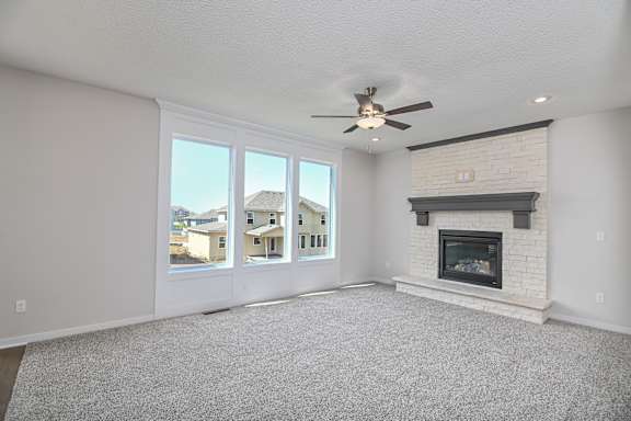 A spacious living room with a fireplace and a ceiling fan.