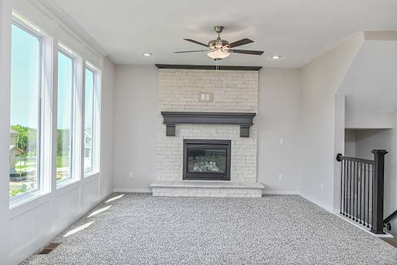 A living room with a fireplace and a ceiling fan.