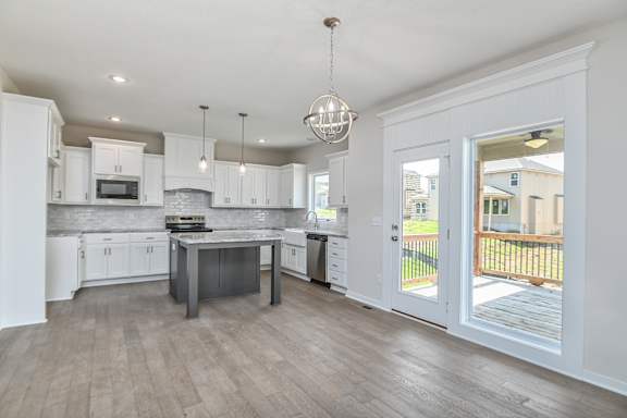 A kitchen with white cabinets and a grey island.