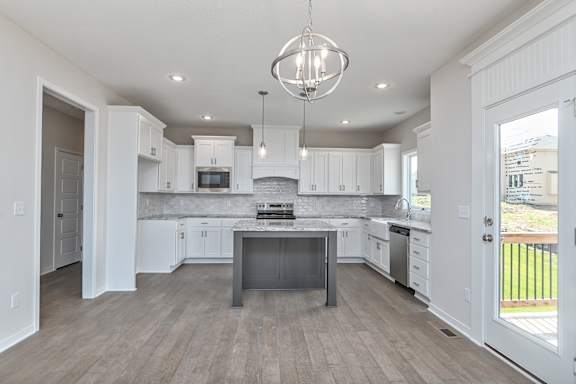 A modern kitchen with white cabinets and a wooden floor.