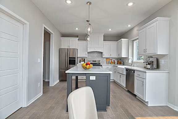 A modern kitchen with a dining table and a white chair.