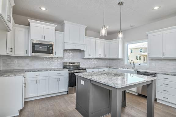A kitchen with a granite countertop and stainless steel appliances.