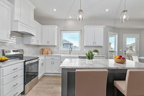 A kitchen with white cabinets and a marble countertop.