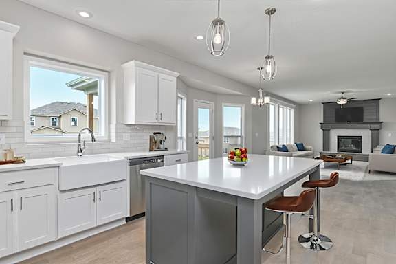 A modern kitchen with a large island and a view of a house across the street.