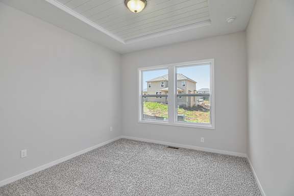 A room with a window showing a view of a house.