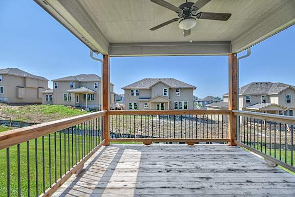 A wooden deck with a fan and houses in the background.