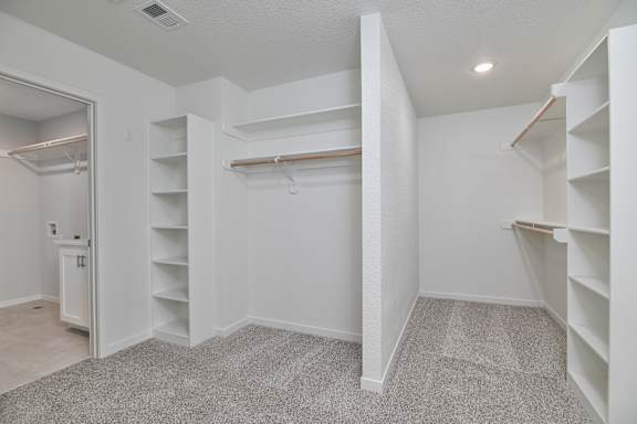 A white room with a carpeted floor and white shelves.