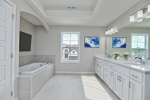 A white bathroom with a large tub and a window.
