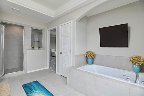 A bathroom with a white tub and a blue vase.