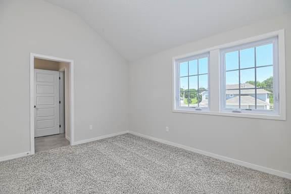A room with a carpeted floor, a door, and a window.