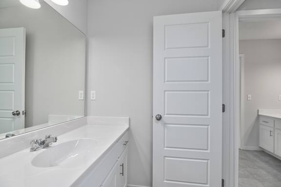 A white bathroom with a sink and mirror.
