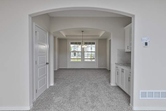 A spacious room with a carpeted floor and white walls.